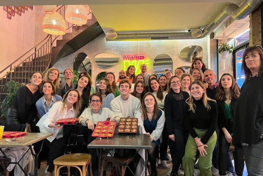 Un groupe de collaborateurs d’entreprise prend la pose, fièrement, autour de plats qu’ils ont réalisés dans le cadre d’un team building solidaire avec Lutila.