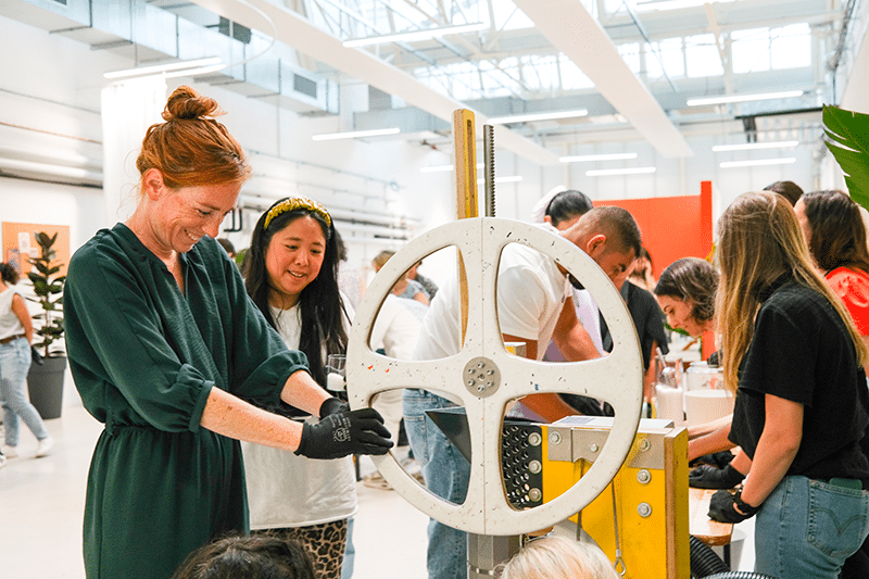 Une collaboratrice d’entreprise utilise du matériel de bricolage, sous les conseils avisés d’une animatrice, dans le cadre d’un team building solidaire et DIY organisé par Lutila.