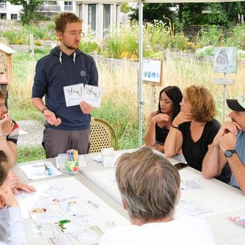 Des collaborateurs d’entreprise réfléchissent autour d’une table, lors d’un atelier pédagogique de sensibilisation aux questions écologiques et à l’économie circulaire.