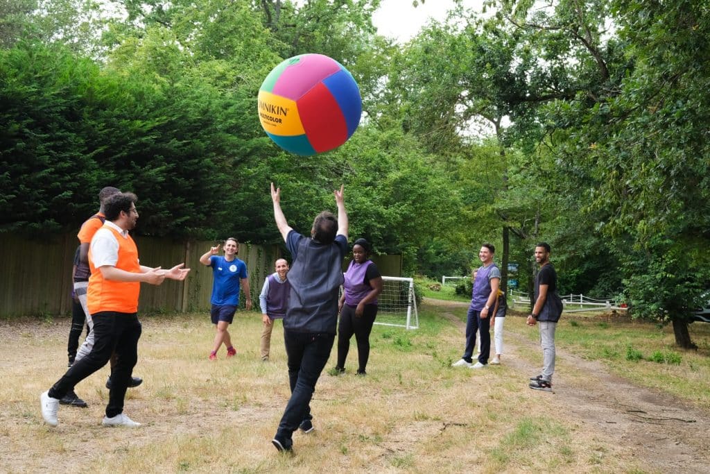 Des collaborateurs d’entreprise et des bénéficiaires d’une association jouent en équipe au Kinball, dans le cadre d’un séminaire sportif et solidaire organisé par Lutila.