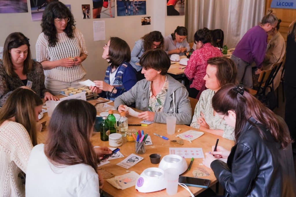 Des collaboratrices d’entreprise sont réunies autour d’une table pour fabriquer des kits de soin à destination de publics précaires, dans le cadre d’un team building solidaire organisé par Lutila.