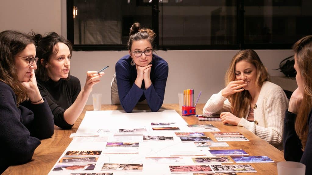 Des collaboratrices d’entreprise participent à une Fresque des nouveaux récits, un atelier de sensibilisation aux comportements humains problématiques pour l’environnement.